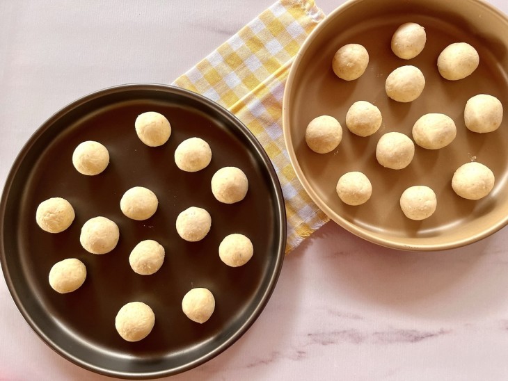 Duas formas contendo bolinhas de pães de queijo com aveia crus.