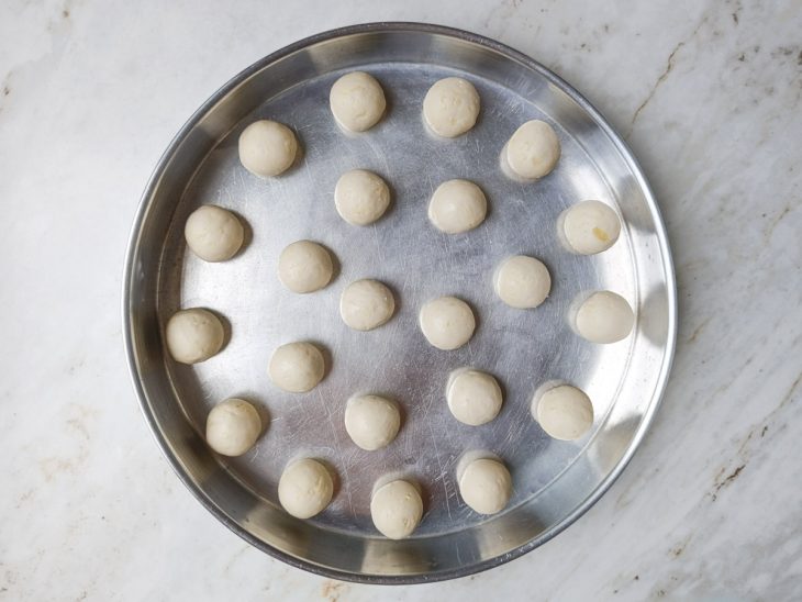 Bolinhas de pão de queijo moldadas sobre a assadeira.