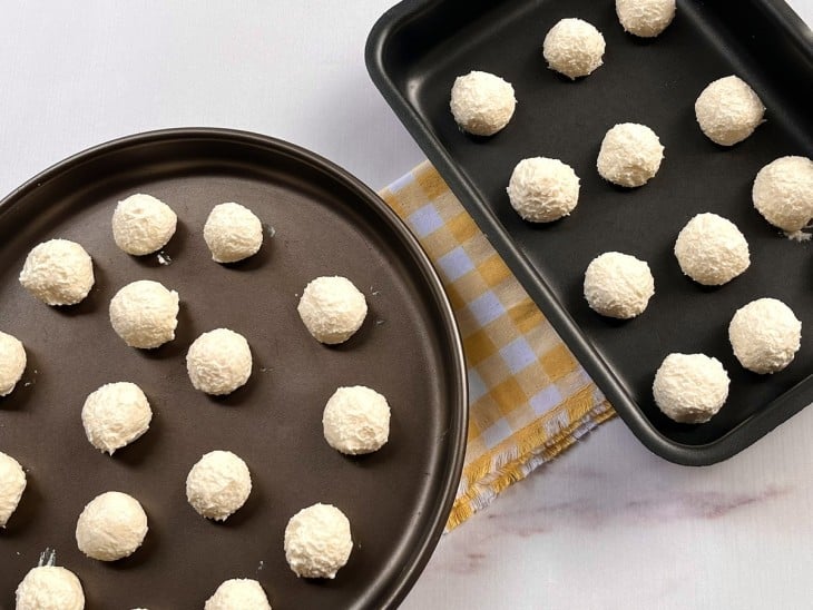 Duas formas contendo as bolinhas cruas de pão de queijo.