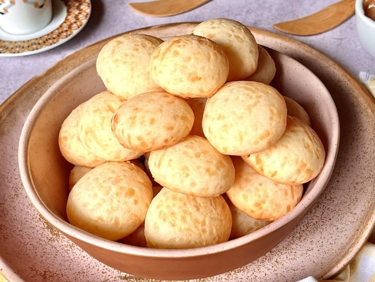 Um recipiente contendo vários pães de queijo com tapioca.