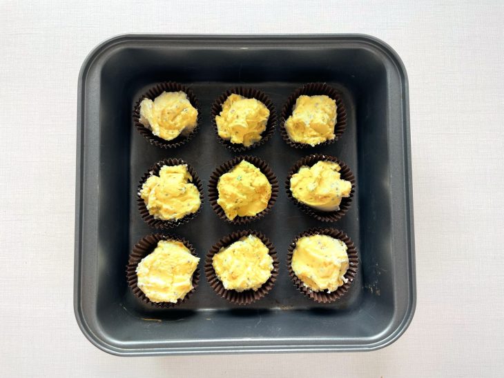 Massa sendo colocada em forminhas de cupcake untadas.