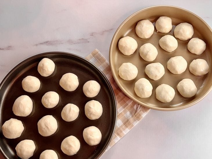 Duas formas contendo bolinhas de pão de queijo.