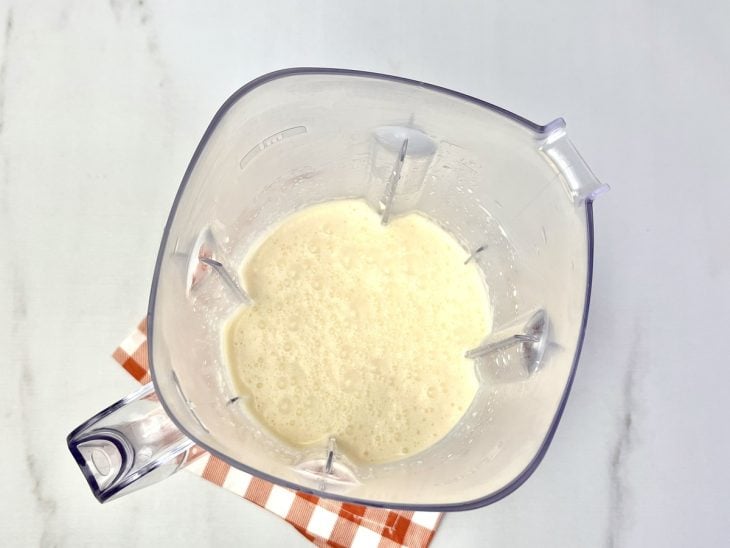 Um liquidificador com a mistura de ovos, óleo, leite, sal e queijo parmesão.