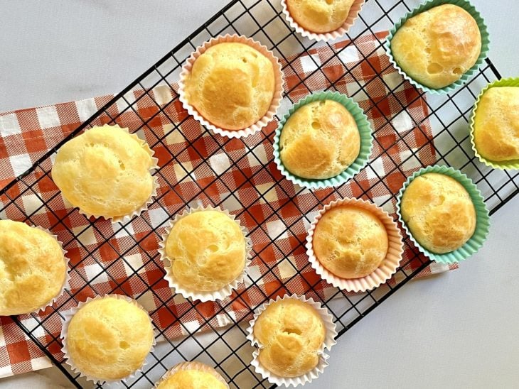 Uma grade com forminhas contendo pão de queijo.