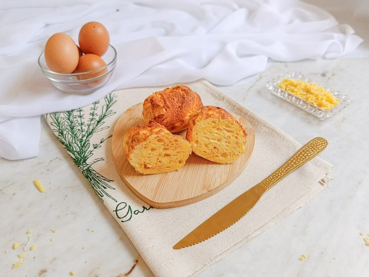 Pães prontos, servidos em tábua, um cortado ao meio.