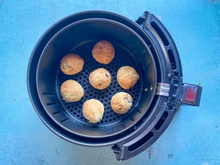 Uma cesta de airfryer contendo pães de queijo recheados.