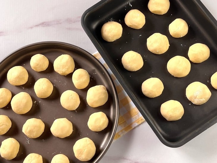 Pães de queijo em duas assadeiras.