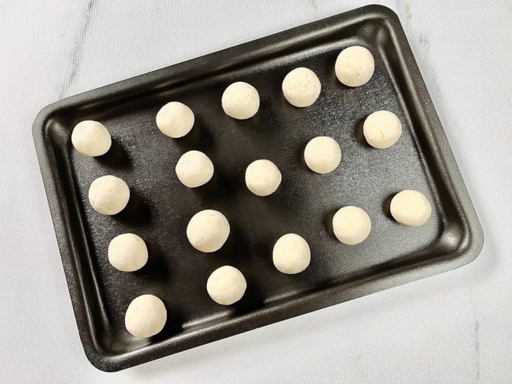 Uma assadeira com porções de pão de queijo.