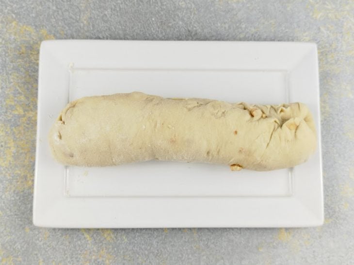 Massa aberta com rolo e modelada em formato de pão.