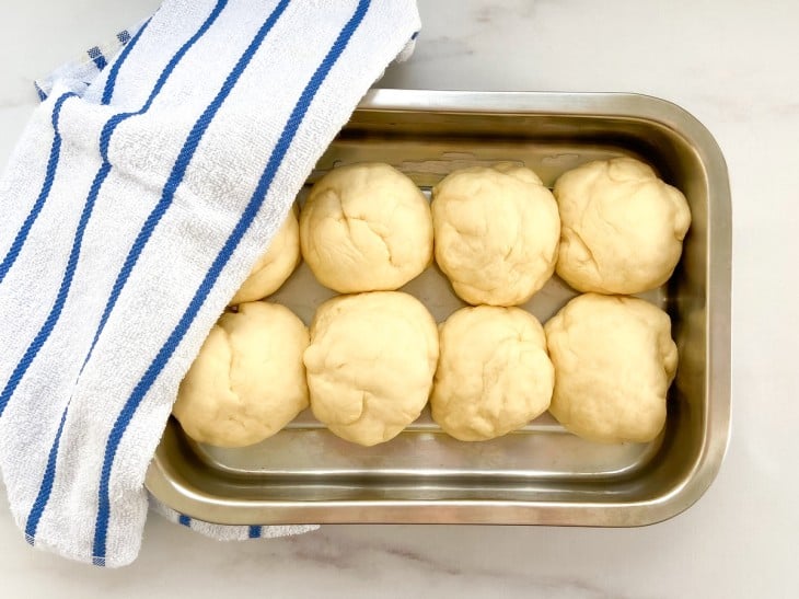 Uma forma contendo vários pãezinhos crus.