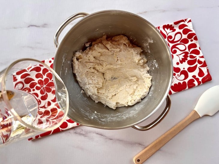 Tigela com massa de pão e água sendo adicionada.