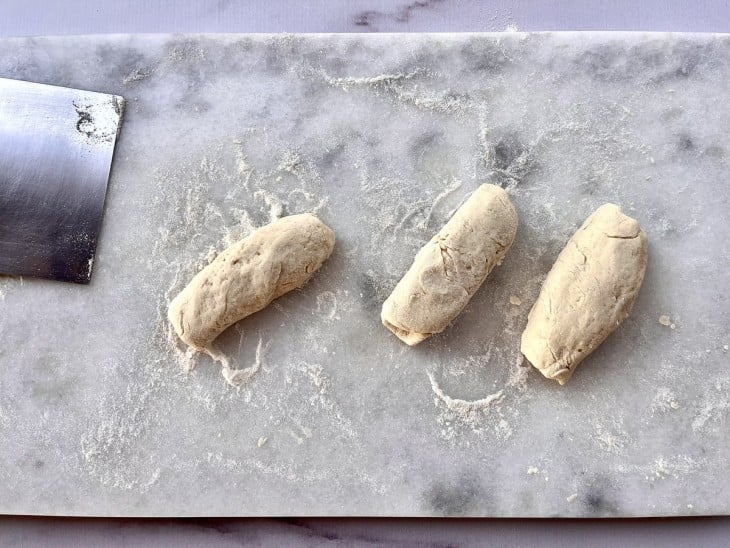 Três porções de massa em formato de pães.