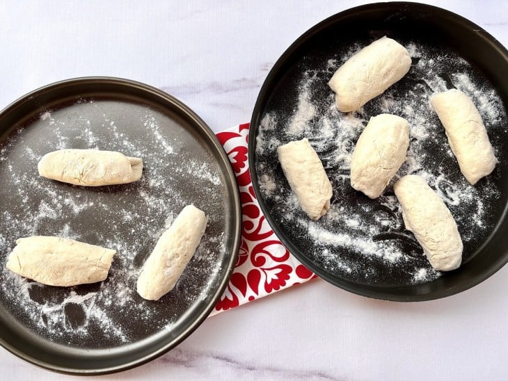 Massa em formatos de pães dispostas em duas formas.