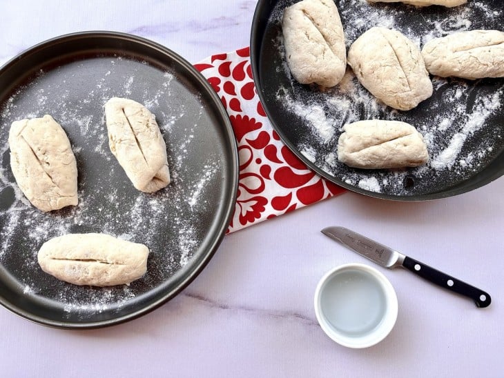 Corte do pão francês feito em cima das porções de massas.