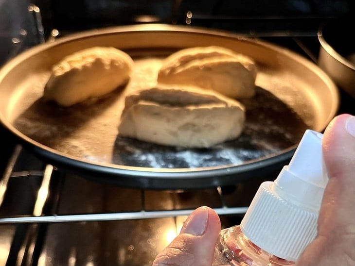 água sendo borrifada nos pães dentro do forno.