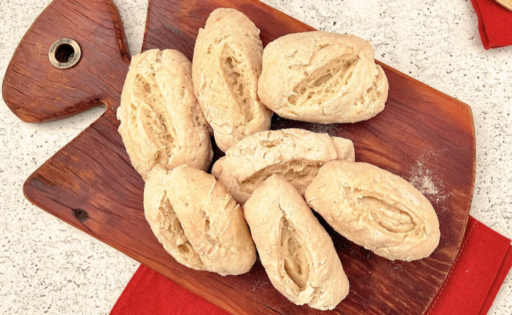 Porção de pão francês sem glúten disposto em uma tábua de madeira.