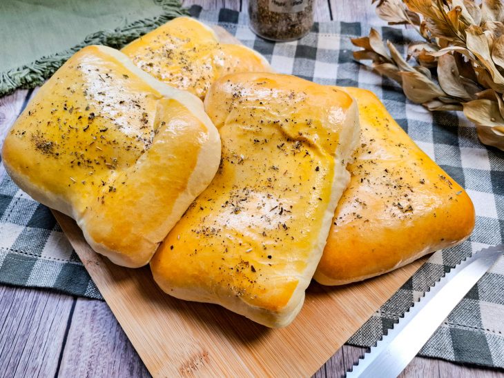 Pães pizza prontos para consumo sobre uma tábua.