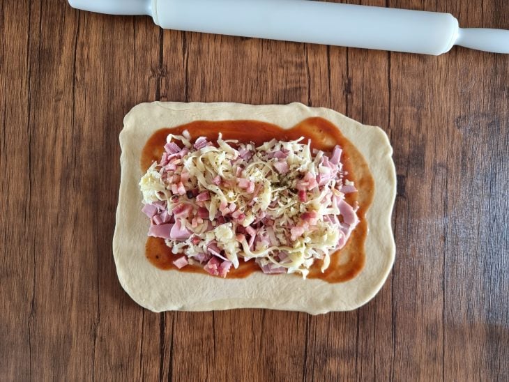 Molho de tomate espalhado e recheio colocado por cima.