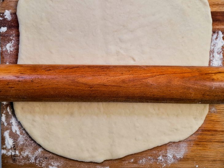 massa de pão aberta com ajuda de rolo de macarrão.