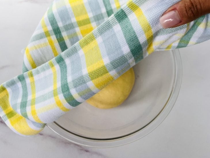 Um recipiente enfarinhada contendo uma massa coberta com pano.