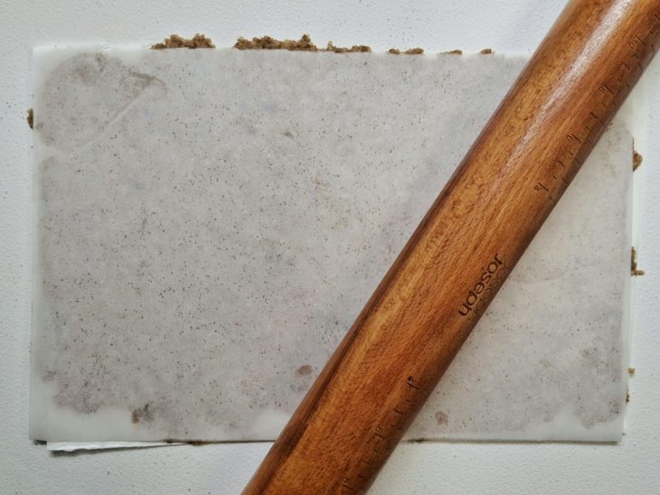 Massa aberta com o rolo abaixo do papel-manteiga.