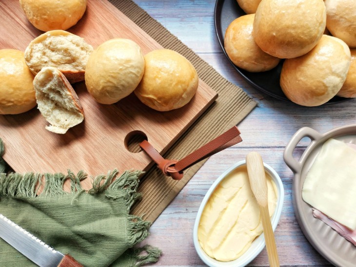 Uma tábua com diversos pãezinhos de cebola.