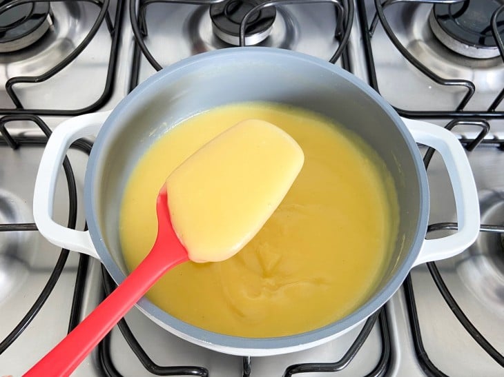 Líquido amarelo de milho engrossado na panela.