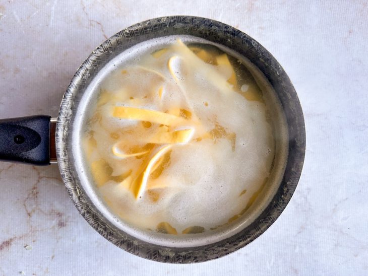 Pappardelle sendo cozido em panela com água até atingir o ponto al dente.