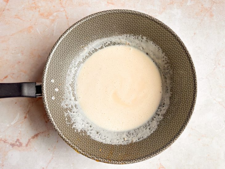Leite sendo incorporado aos poucos para formar um molho branco cremoso.