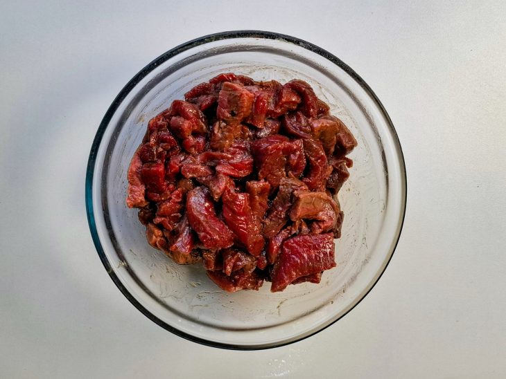 Filé mignon cortados me cubos, numa tigela, com sal, pimenta e azeite.