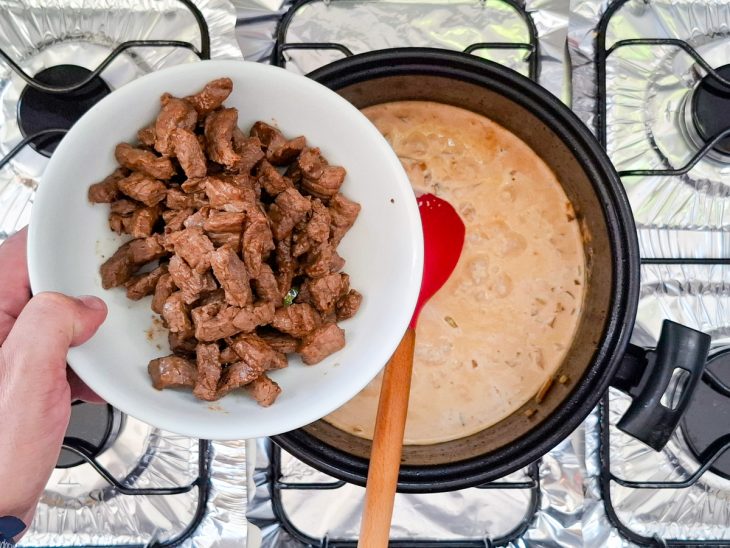 Carne sendo adicionada novamente na panela, junto ao molho.