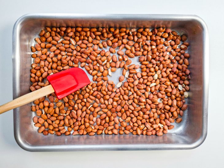 Amendoim cru espalhado uniformemente em assadeira.