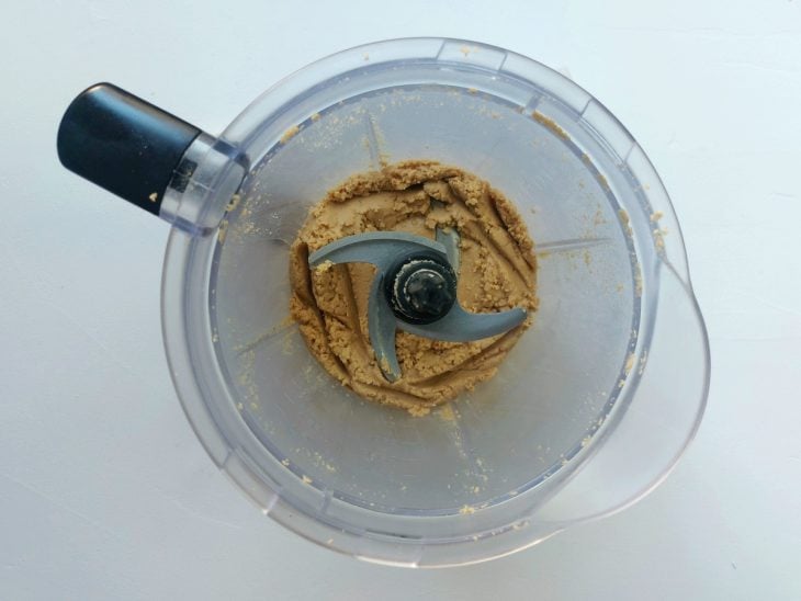 Um processador de alimentos com amendoim triturado formando a pasta.