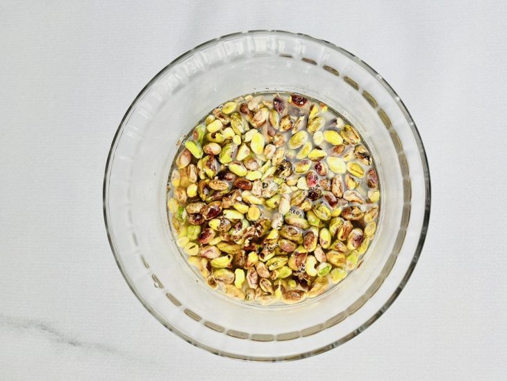 Numa tigela com água, os pistaches de molho.