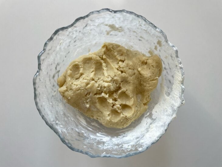 Creme de leite, manteiga, açúcar, sal e farinha sendo misturados em uma tigela até formar uma massa homogênea.