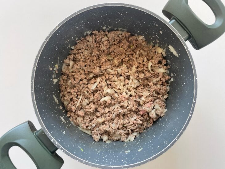 Carne moída sendo refogada com azeite e vinagre até ficar soltinha e dourada.