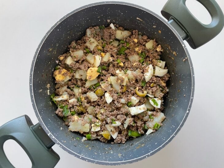 Recheio recebendo os temperos e sendo misturado para incorporar os sabores.