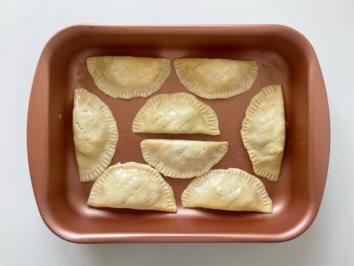 Pastéis sendo fechados e recebendo acabamento decorado nas bordas.