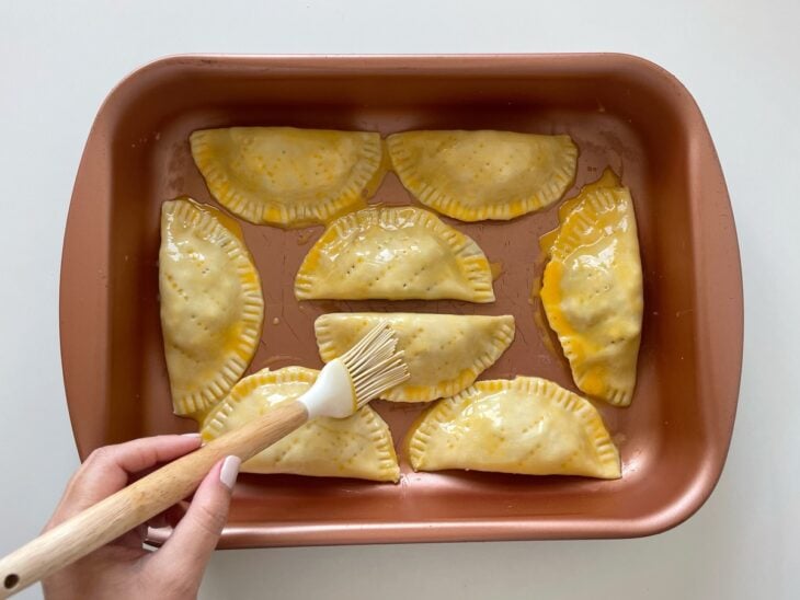 Mistura de gema sendo pincelada sobre a superfície dos pastéis.