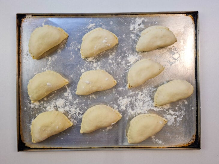 Pastéis modelados organizados em forma enfarinhada antes da fritura.