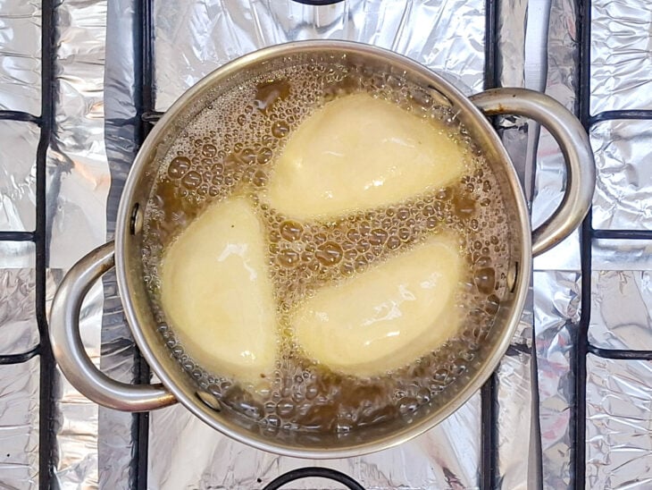 Pastéis fritando em óleo aquecido até ficarem dourados e inflados.