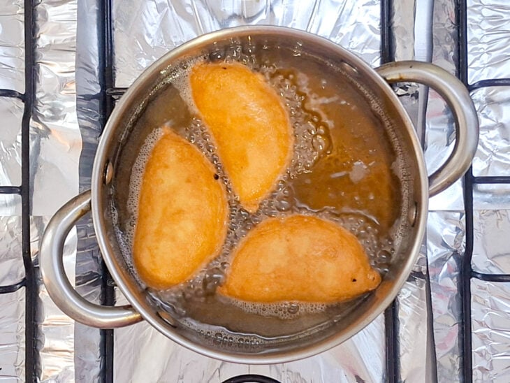 Pastéis sendo virados durante a fritura para dourar dos dois lados.