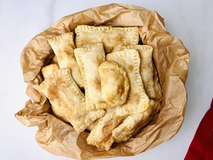 Um recipiente contendo pastel com recheio de queijo e batata palha.