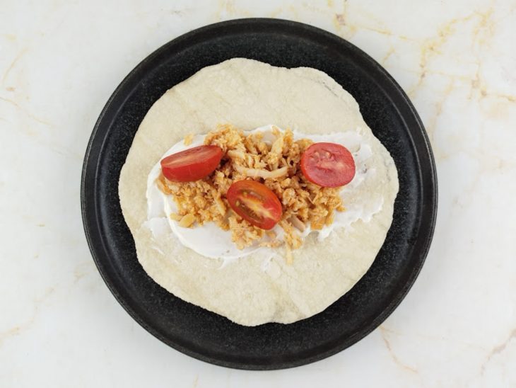 Frango desfiado e tomate acomodados no centro da massa.