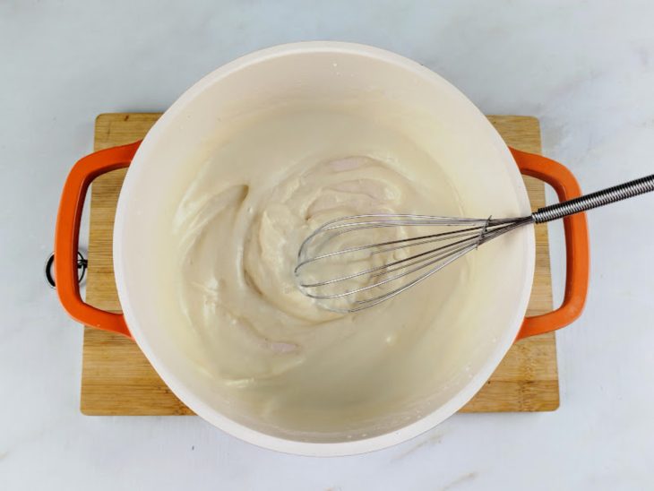 Uma panela com o creme ao ponto, misturado com fouet.