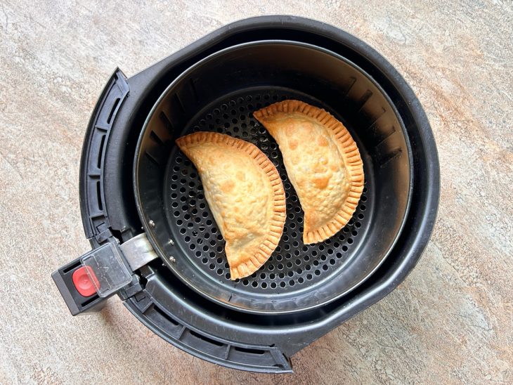 Dois pastéis assando na air fryer.