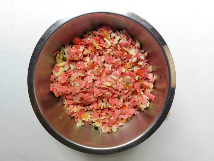 Um recipiente contendo a mistura de mortadela, mussarela, tomate, cebola, salsinha e sal.