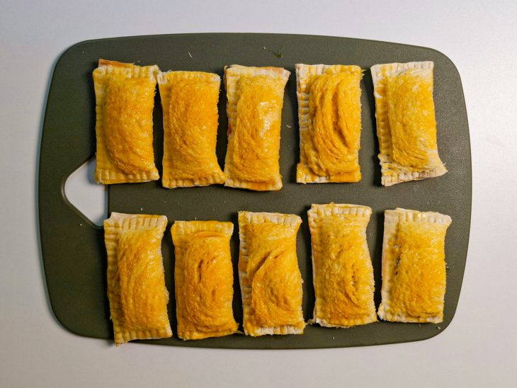 Pastéis montados sendo pincelados com gema de ovo.