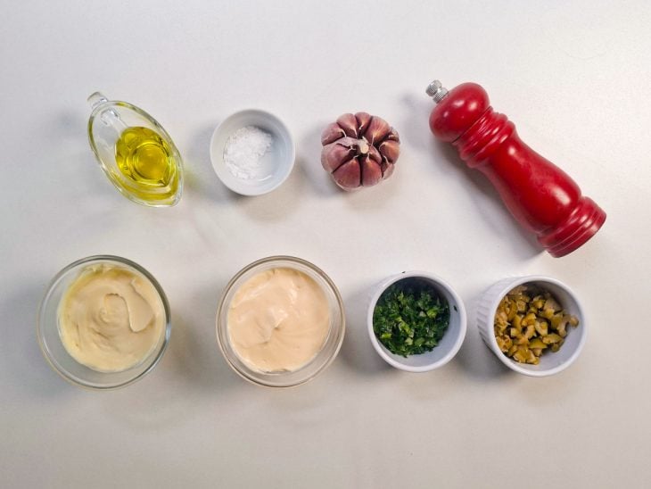 Ingredientes separados na bancada com alho, azeite, ervas e potes de acompanhamento.