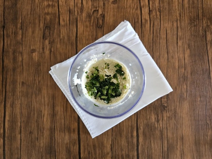 Um recipiente com o patê, queijo parmesão, o chimichurri e salsinha.